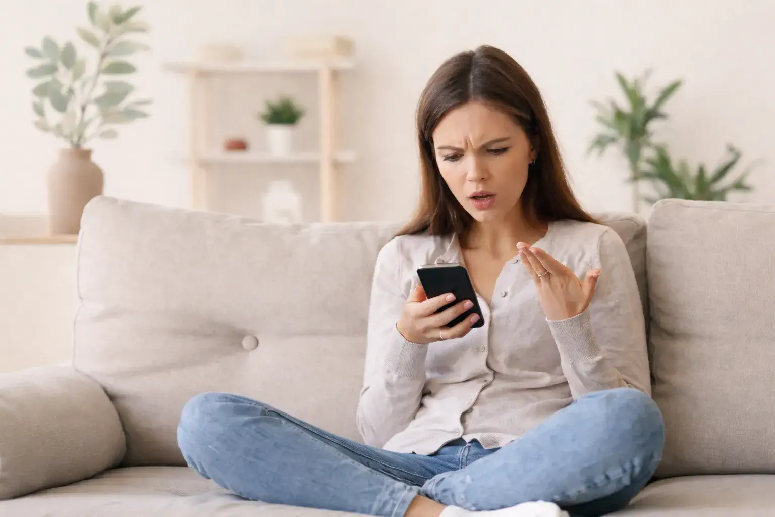 Burn-out et irritabilité : femme épuisée assise sur un canapé, tendue face à son téléphone
